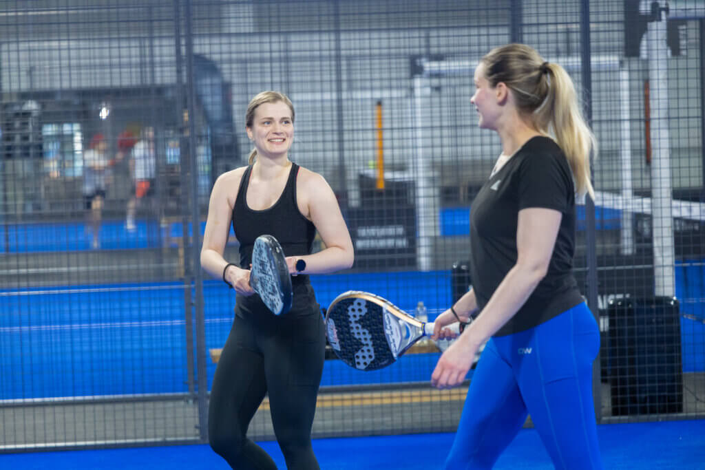 Naiset pelaamassa padelia Padel Club Kuopion sisäkentällä.